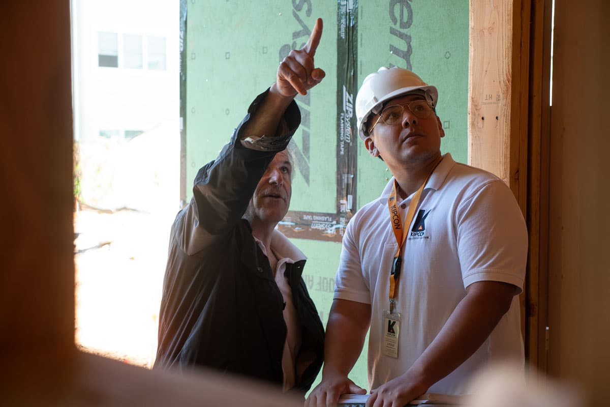 Two construction workers pointing upward